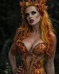 GRID THUMBNAIL — A fae woman with fiery orange hair wears an antlered leaf crown and jewel-encrusted autumn corset, posed in a dim forest setting.