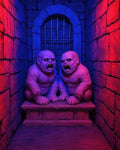 GRID THUMBNAIL — Two snarling demonic twins crouch on a stone plinth in a narrow dungeon alcove before iron bars, lit by eerie red and blue light.